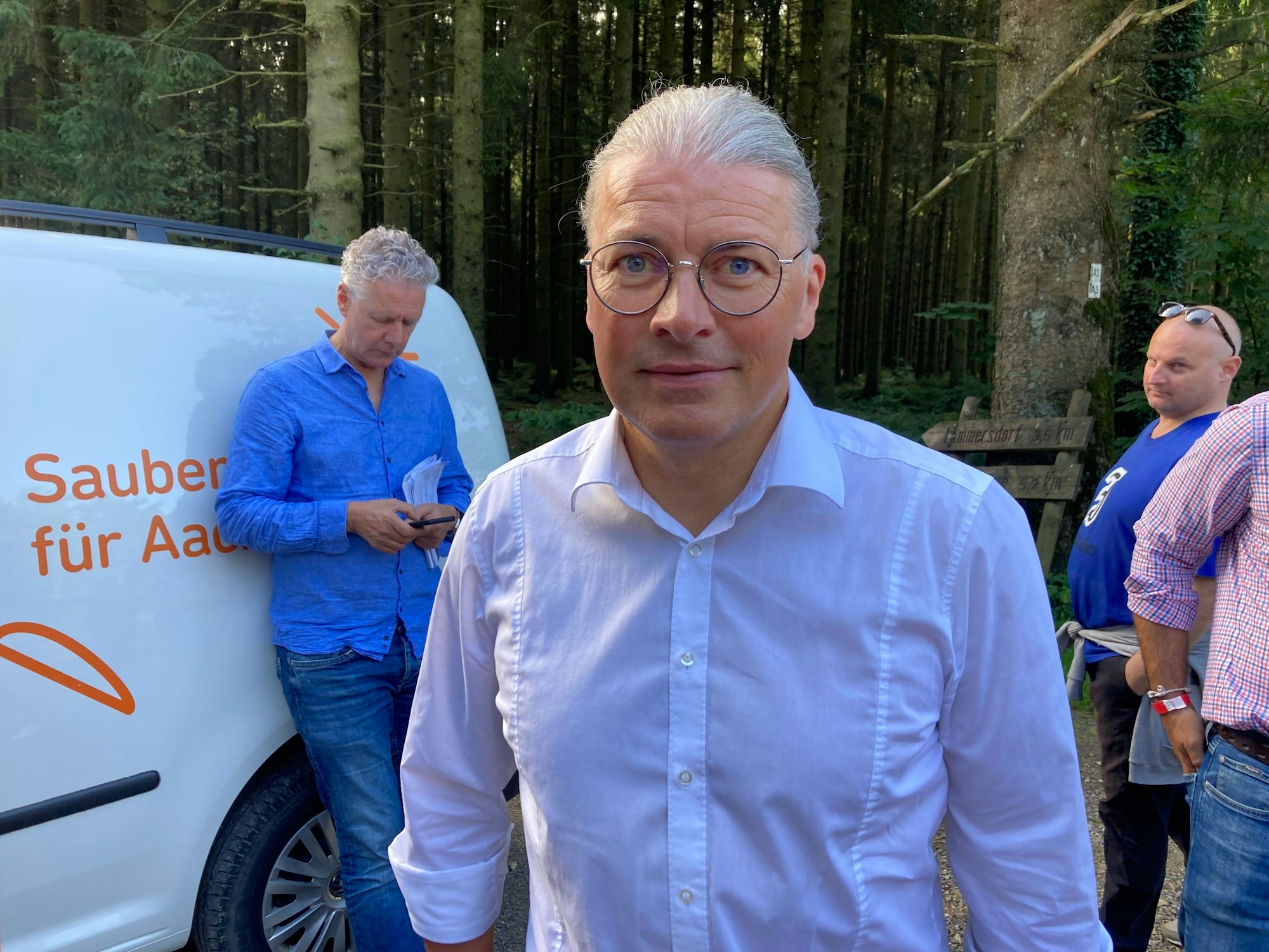 Bernd Goffart (CDU), Bürgermeister von Simmerath, ist im Porträt zu sehen. Hinter ihm einige andere Personen und Wald.