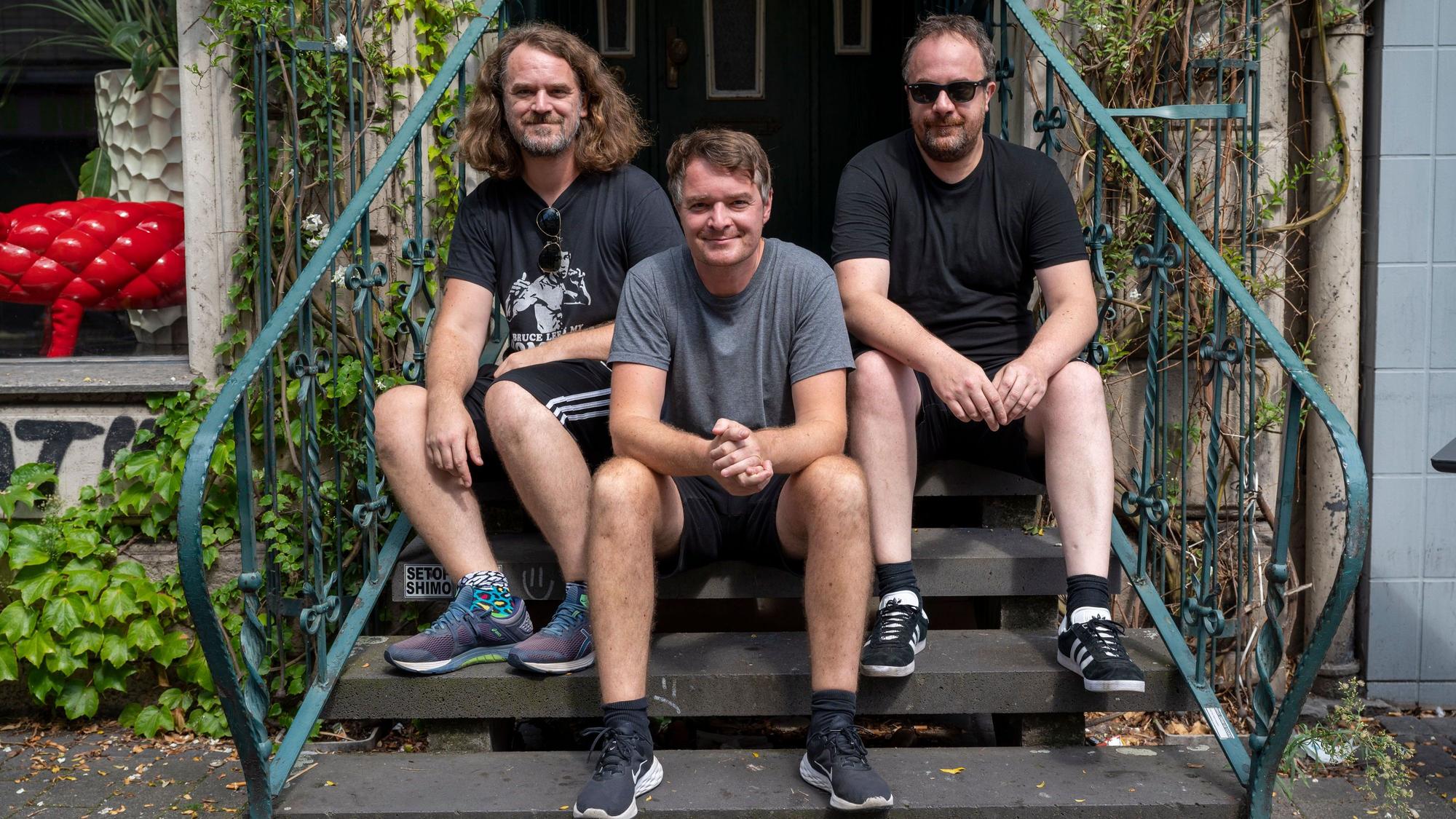 Sascha, Sebastian und Johannes Madsen sitzen auf einer Treppe und schauen in die Kamera.