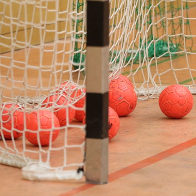 Das Bild zeigt zahlreiche Handbälle in einem Tor.