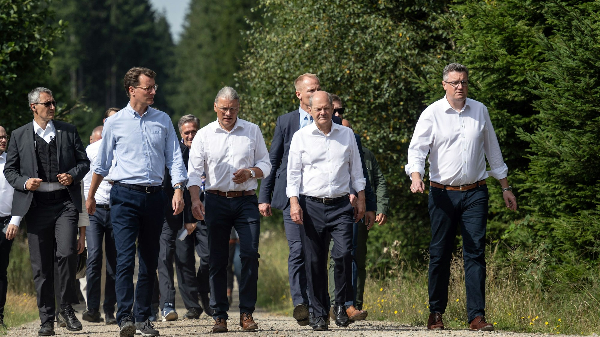 Spaziergang im Windpark:  Bundeskanzler Olaf Scholz (SPD, 2.v.r.) und Hendrik Wüst (2.v.l.), Ministerpräsident von Nordrhein-Westfalen, und Bernd Goffart, Bürgermeister (M., beide CDU) sind bei ihrer Tour in der Eifel zu sehen.