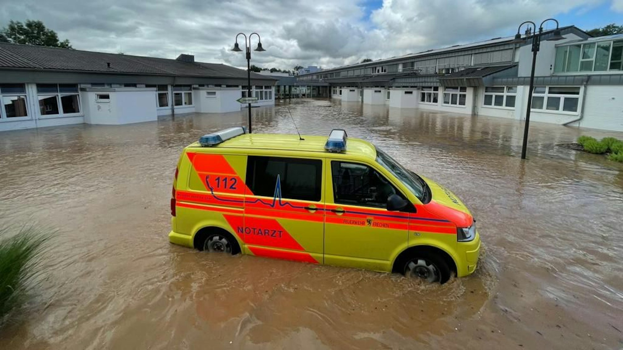 Das Bild zeigt einen Notarztwagen im Wasser vor dem Marien-Hospital in Erftstadt.