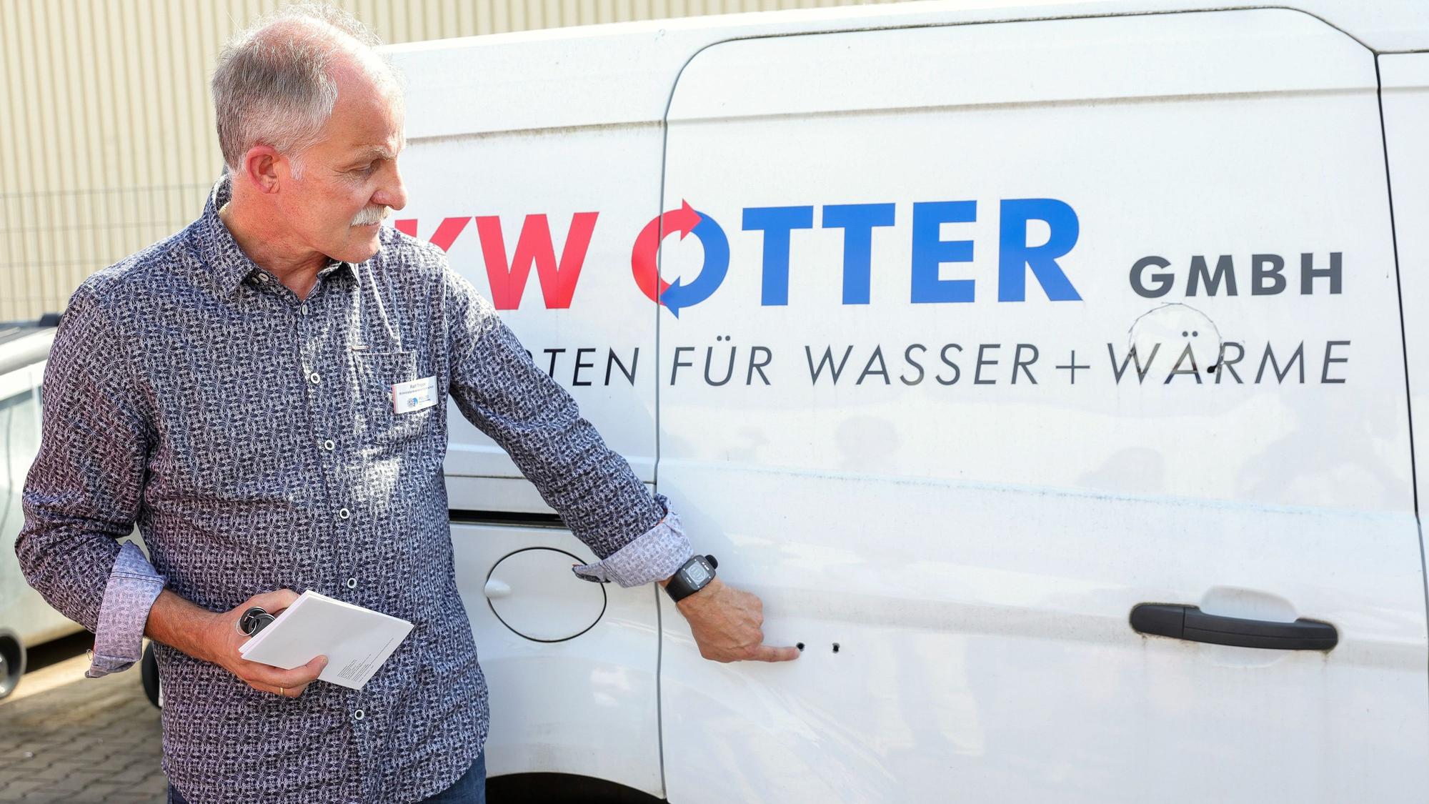 Ralf Trippe von der Polizei Köln zeigt zwei Bohrlöcher in einer Seitentür eines Handwerkerautos, über die die Täter die Schiebetür aufgebrochen haben.