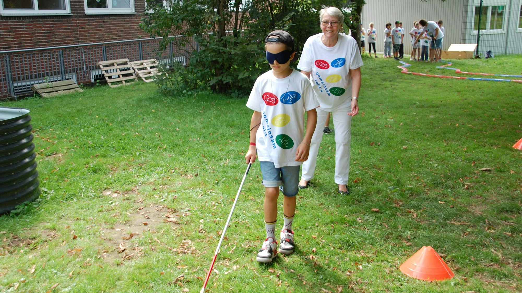 Schüler mit Blindenstock in einem Parcours im Schulgarten.
