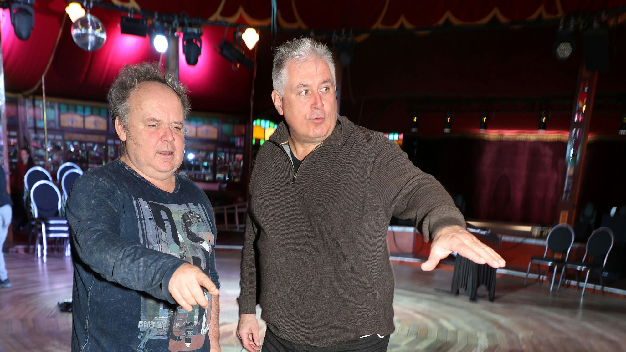 Zwei Männer stehen in einem Spiegelzelt und besprechen etwas.