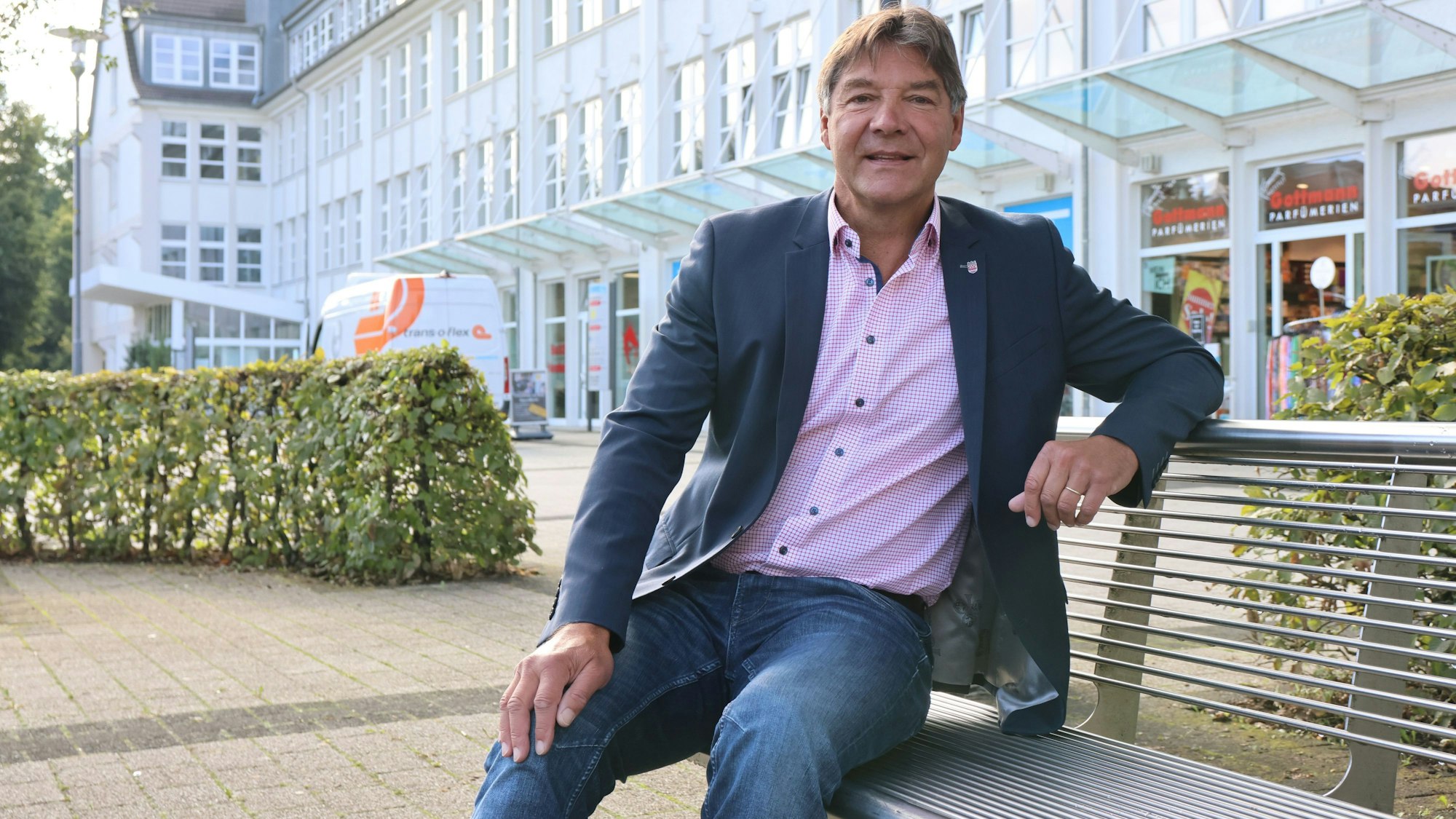 Zu sehen ist ein Mann, der vor dem Rathaus in Bergneustadt auf einer Bank sitzt.