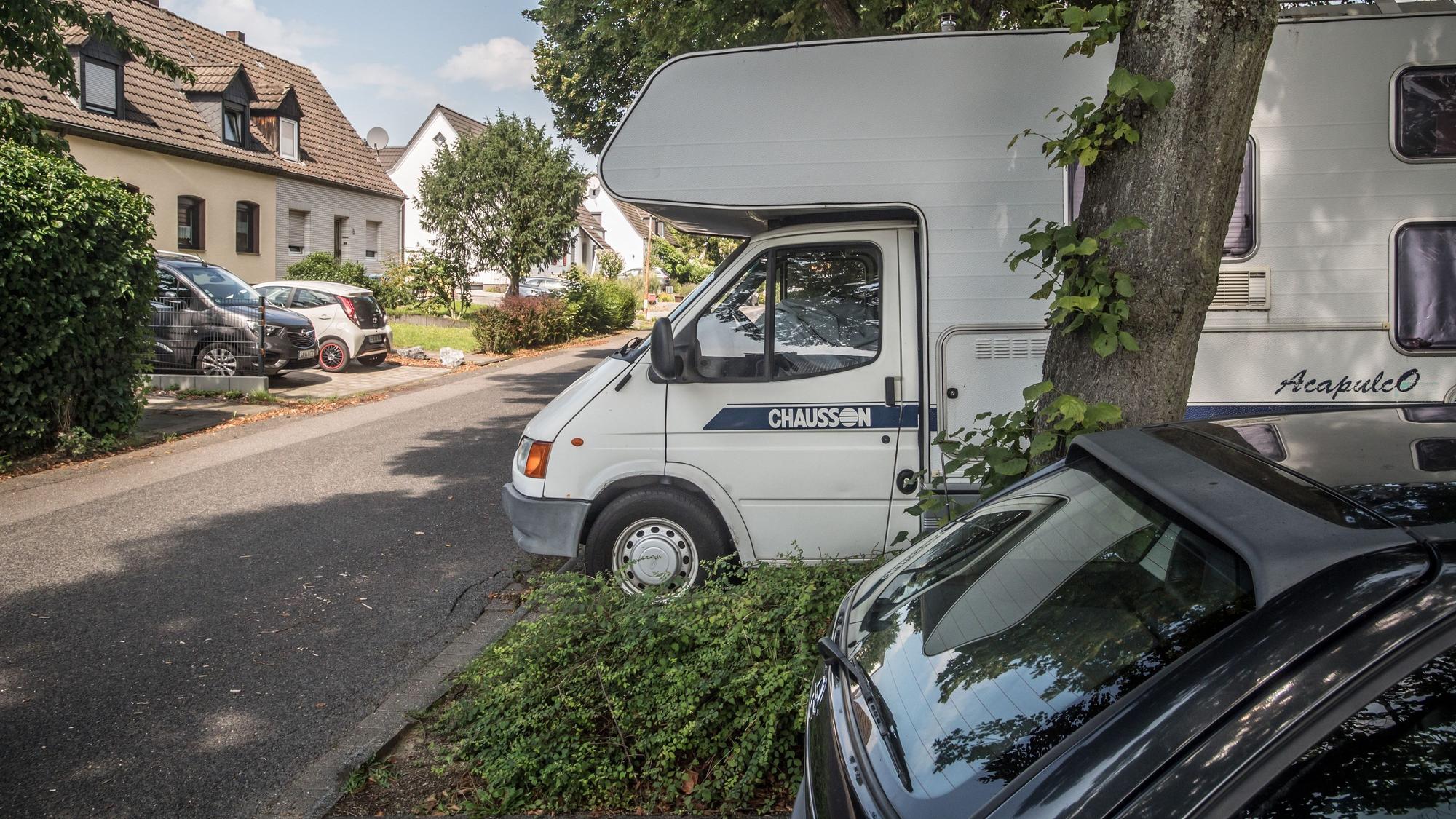 Ein Wohnmobil im öffentlichen Raum auf einem schattigen Parkplatz in Schlebusch.