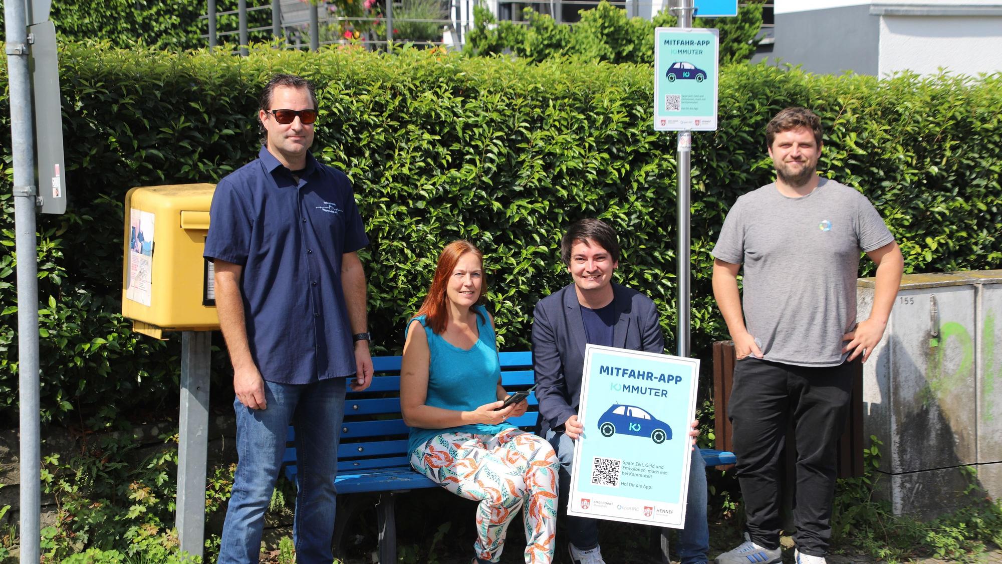 Die Stadt Hennef bietet jetzt die Mitfahrapp Kommuter an, die Mitfahrbänke sind darin enigebunden. An der Mitfahrbank Hennef trafen sich (v.l.): Jens Nowak, Vorsitzender Heimatverein Happerschoß, Klimaschutzmanagerin Annette Flintemann, Bürgermeister Mario Dahm und Martin Stein, Entwickler der App von OpenInc.