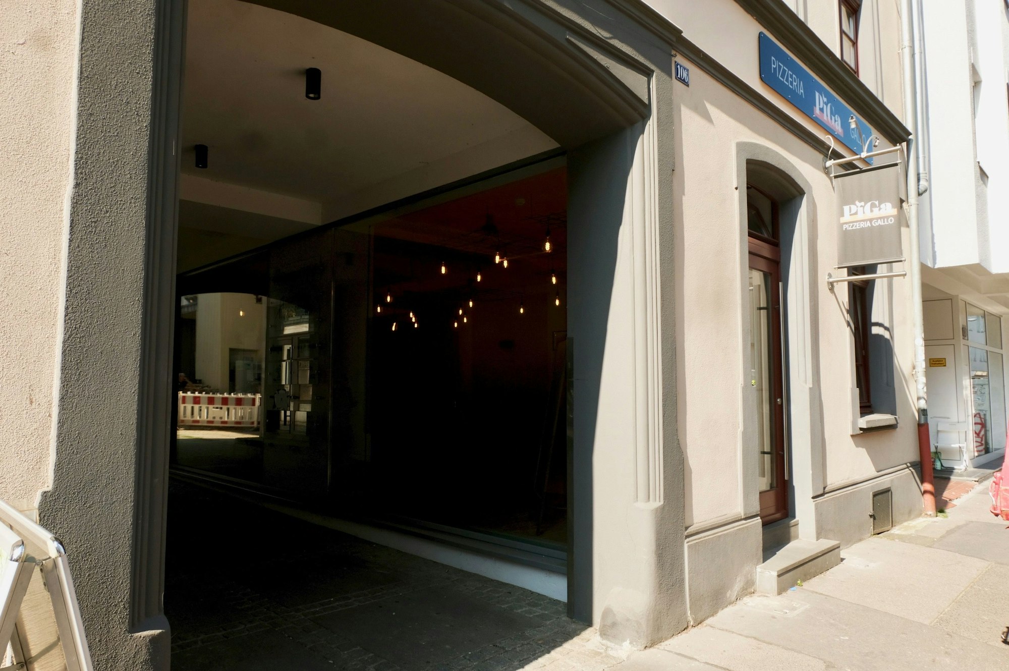 Ein Ladenlokal liegt unmittelbar neben der Einfahrt zu einem Hinterhof.