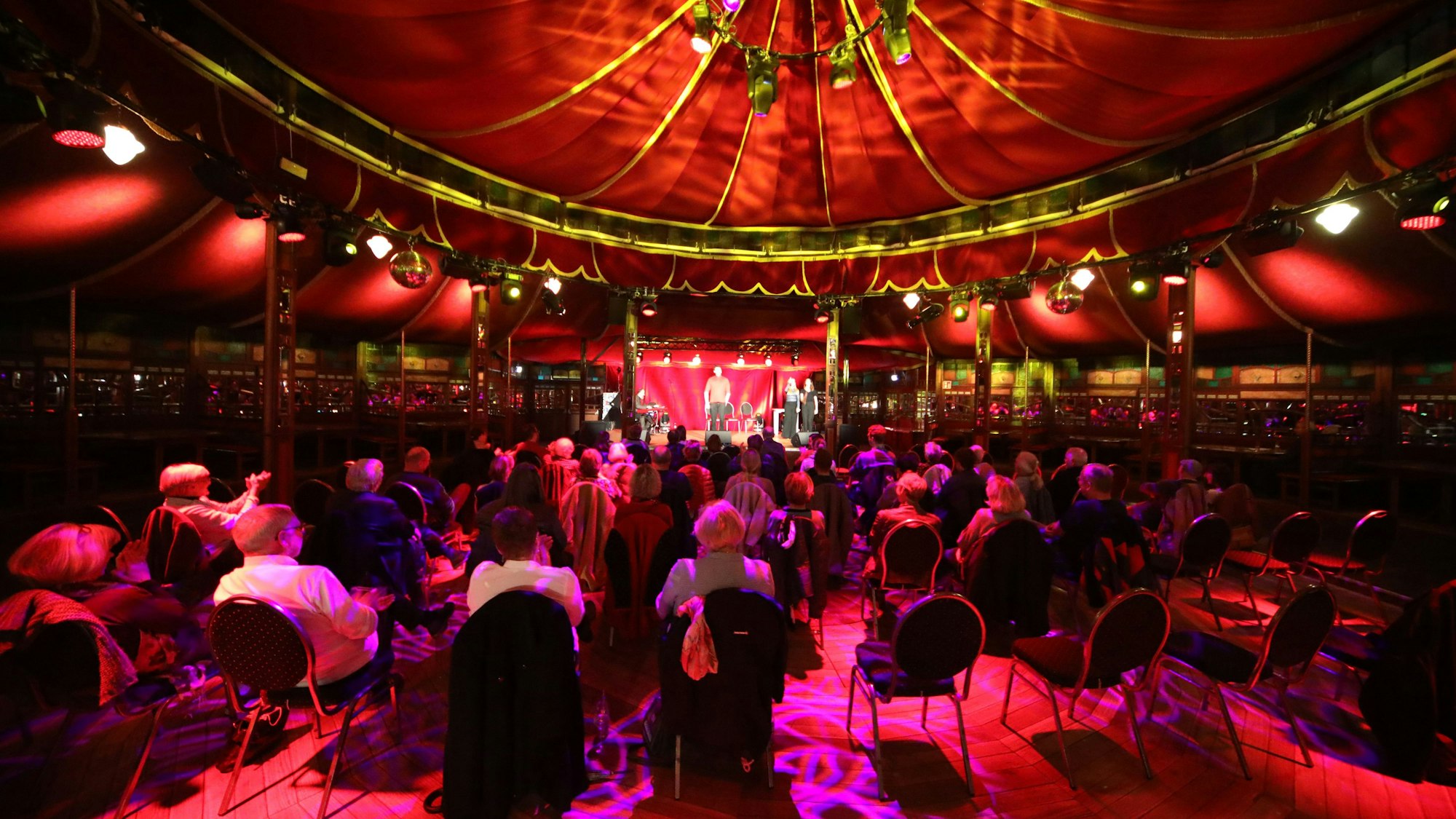 Menschen sitzen im Altenberger Spiegelzelt.