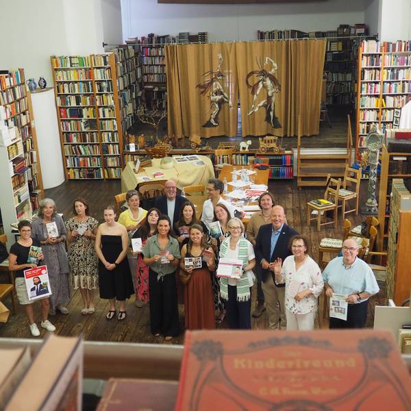 Eine Gruppe Menschen steht zwischen Regalen voller alter Bücher.