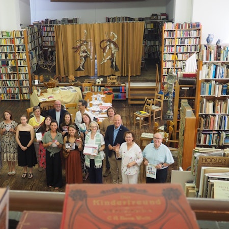 Eine Gruppe Menschen steht zwischen Regalen voller alter Bücher.