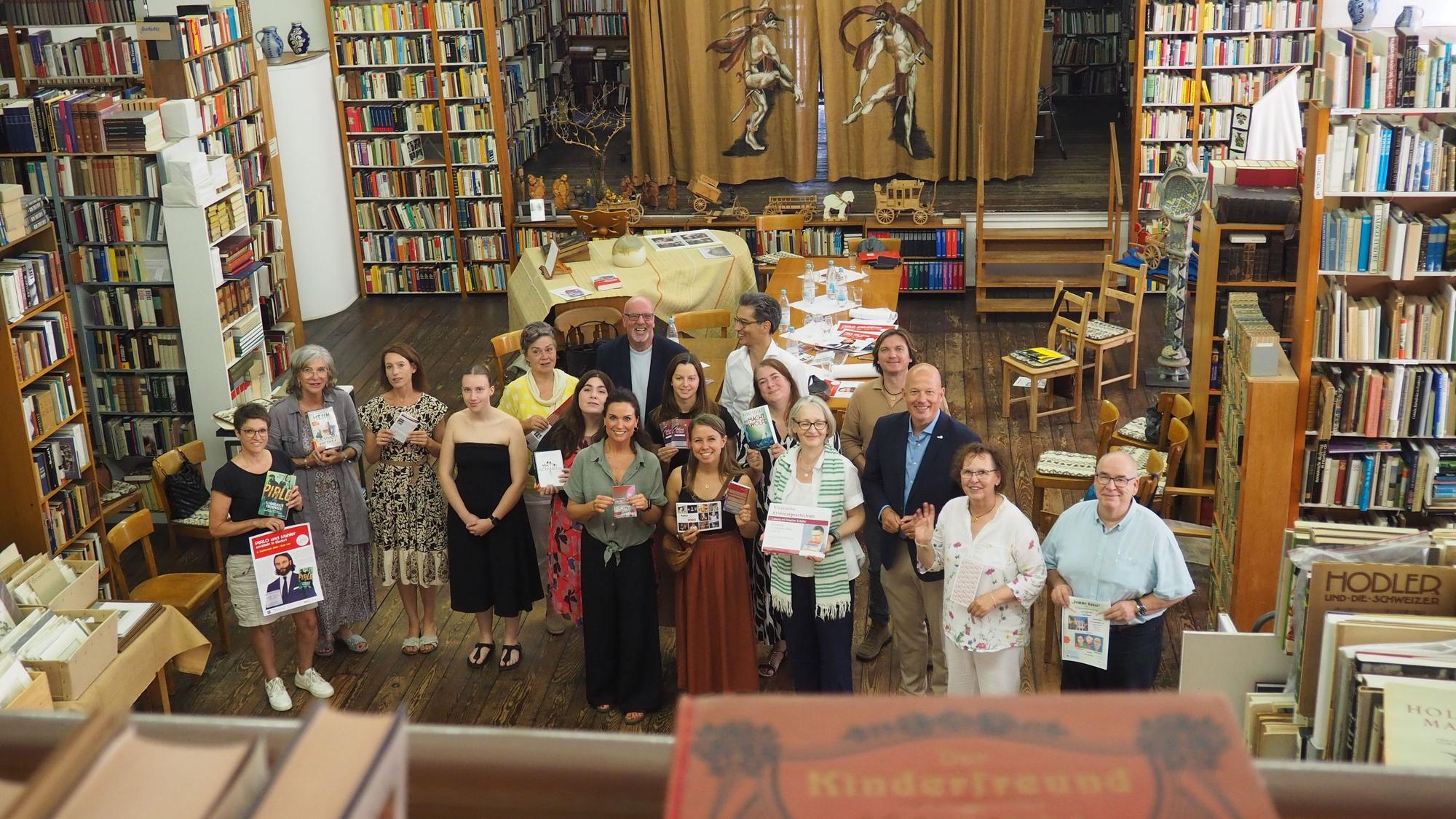 Eine Gruppe Menschen steht zwischen Regalen voller alter Bücher.