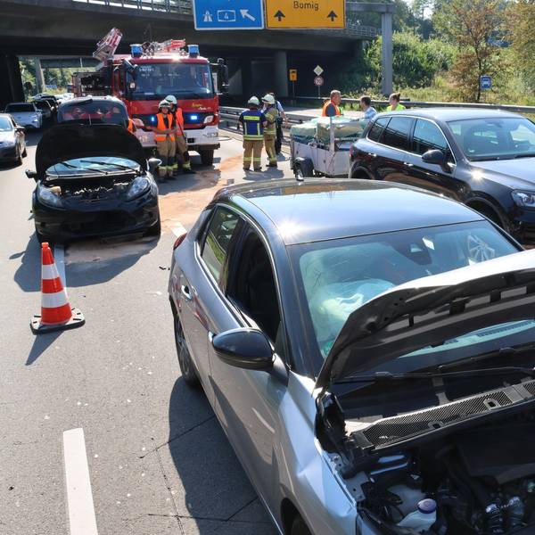 Mehrere beschädigte Autos stehen auf zwei Fahrspuren. Im Hintergrund ist die Feuerwehr zu sehen.