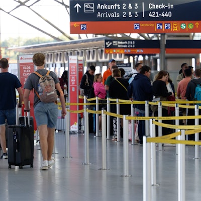 Reisende gehen im Flughafen Köln/Bonn durch die Abflughalle.