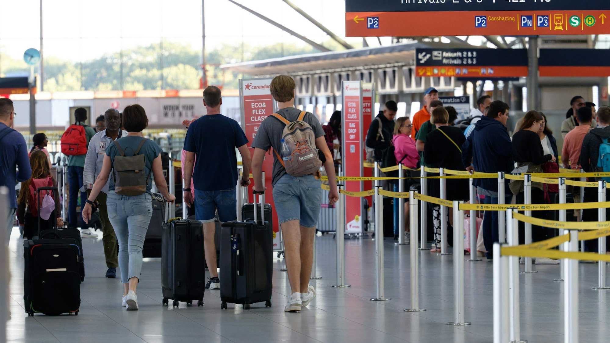 Reisende gehen im Flughafen Köln/Bonn durch die Abflughalle.