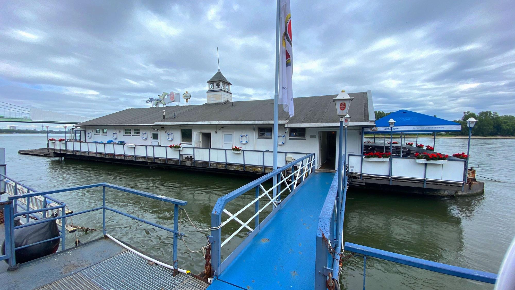 Das auf dem Rhein liegende Bootshaus „Albatros“, unter dichten grauen Wolken
