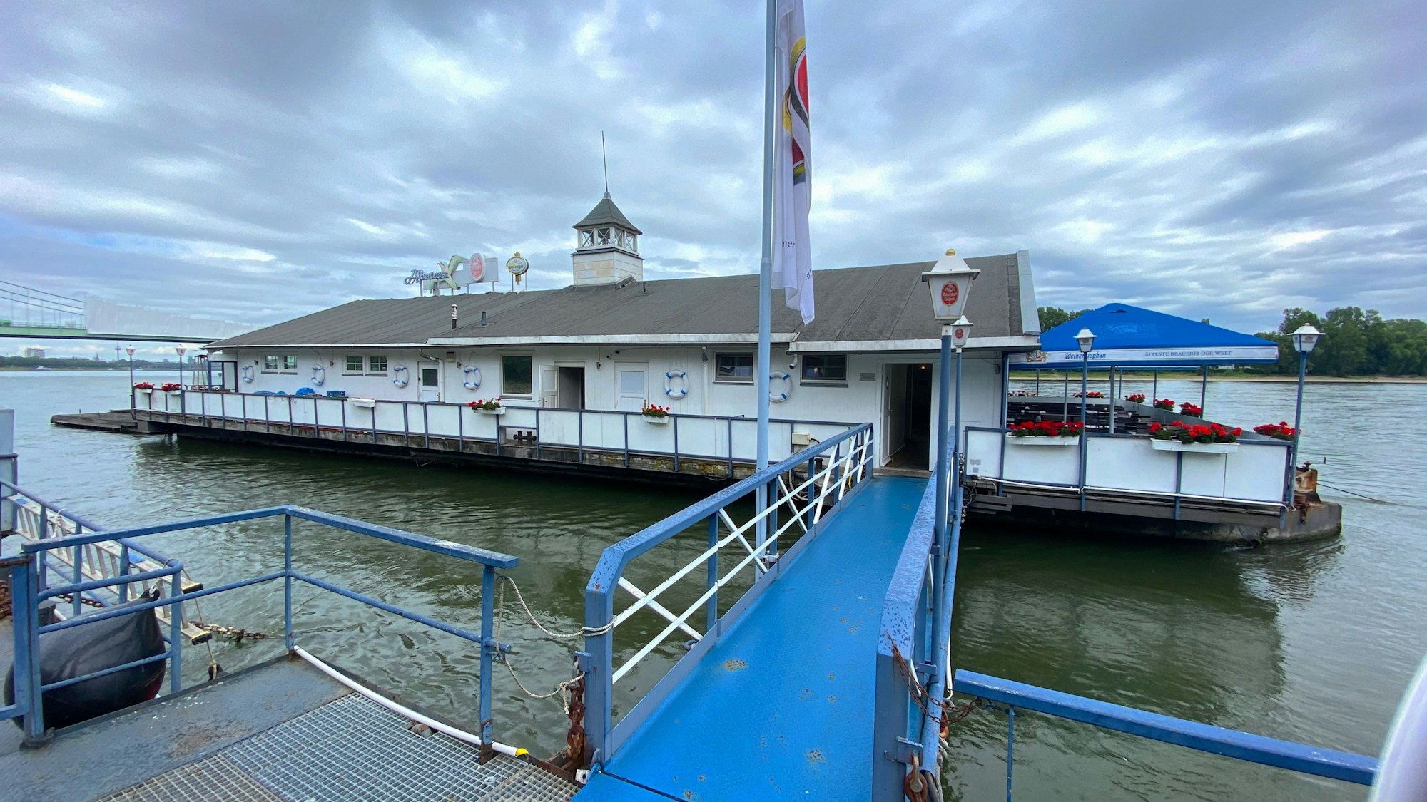 Das auf dem Rhein liegende Bootshaus „Albatros“, unter dichten grauen Wolken