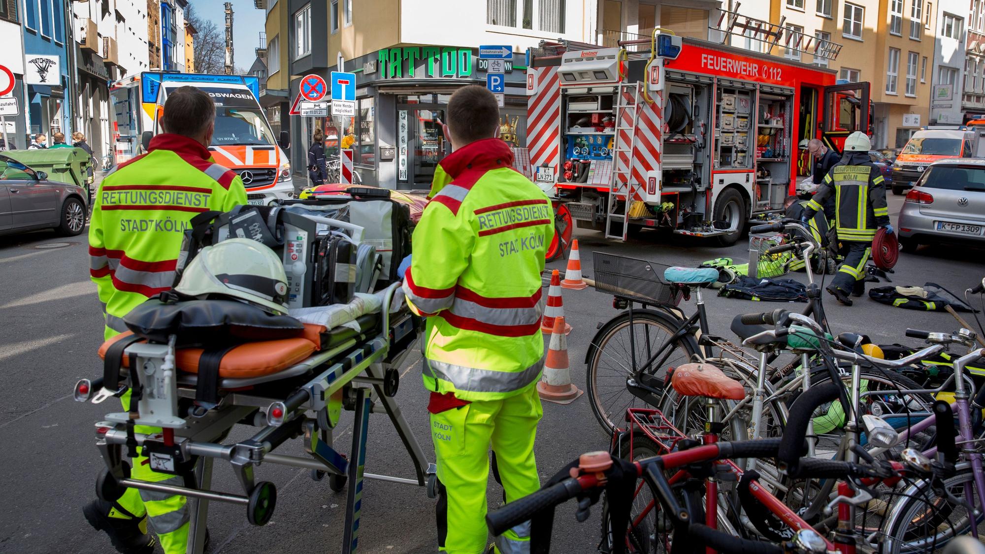 Rettungskräfte der Berufsfeuerwehr stehen bei einem Wohnungsbrand in der Huhnsgasse neben einer fahrbaren Trage.
