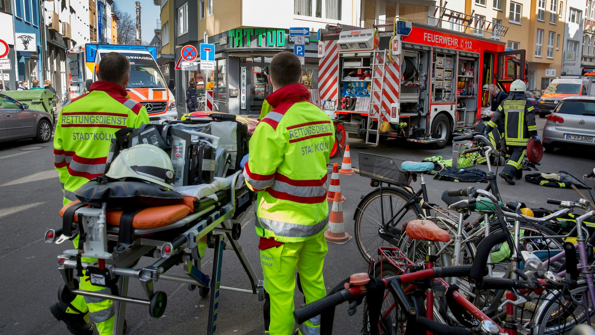 Rettungskräfte der Berufsfeuerwehr stehen bei einem Wohnungsbrand in der Huhnsgasse neben einer fahrbaren Trage.