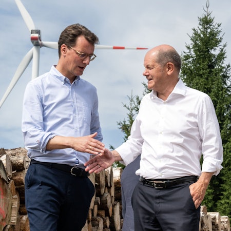 Simmerath: Bundeskanzler Olaf Scholz (SPD, r) und Hendrik Wüst (CDU), Ministerpräsident von Nordrhein-Westfalen, geben sich bei ihrem Besuch eines Bürgerwindparks die Hand. Die Kleinstadt mit über 15 000 Einwohnern erzielt Gewinne durch die Verpachtung der gemeindeeigenen Waldflächen an den Betreiber. Ein Teil der Erträge fließt in den Gemeindehaushalt und ermöglicht niedrige Grund- und Gewerbesteuern.