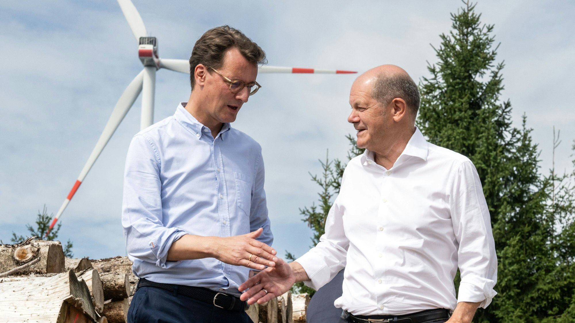 Simmerath: Bundeskanzler Olaf Scholz (SPD, r) und Hendrik Wüst (CDU), Ministerpräsident von Nordrhein-Westfalen, geben sich bei ihrem Besuch eines Bürgerwindparks die Hand. Die Kleinstadt mit über 15 000 Einwohnern erzielt Gewinne durch die Verpachtung der gemeindeeigenen Waldflächen an den Betreiber. Ein Teil der Erträge fließt in den Gemeindehaushalt und ermöglicht niedrige Grund- und Gewerbesteuern.