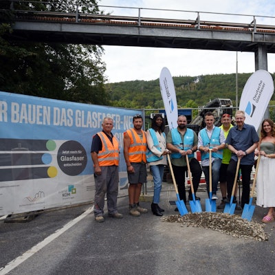 Neun Vertreter von Firmen, der Deutschen Glasfaser und der Stadt Bergneustadt stehen mit Spaten in der Hand auf einer Straße im Gewerbegebiet Pernze.