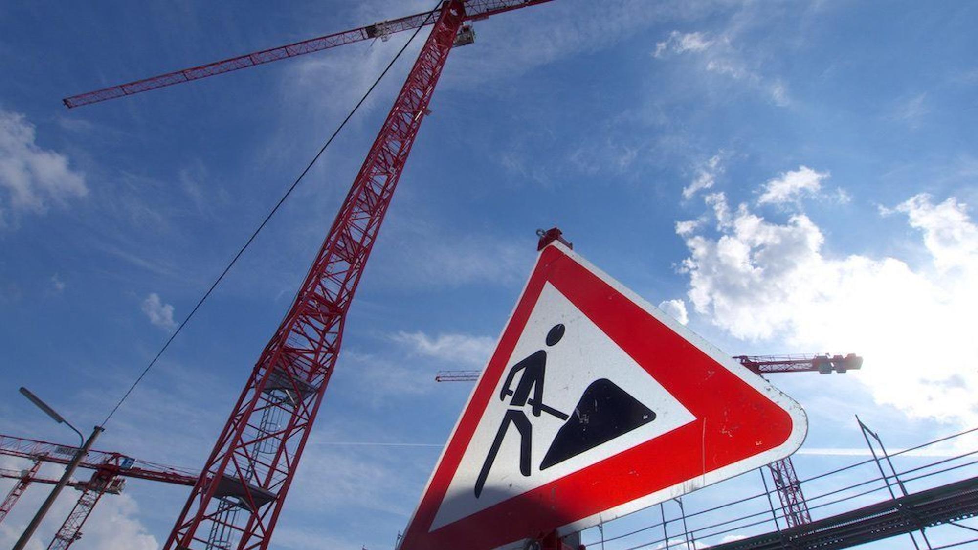 ARCHIV - 15.04.2022, Bayern, München: Ein Baustellenschild und Baukräne im Münchner Stadteil Freiham. Nach mehr als zehn Jahren Immobilienboom in Deutschland und enorm steigenden Preisen erwarten einige Experten eine Wende am Wohnungsmarkt. (zu dpa "Zinsanstieg, teures Bauen, Lieferengpässe - Kippt der Immobilienboom?") Foto: Carsten Hoefer/dpa +++ dpa-Bildfunk +++