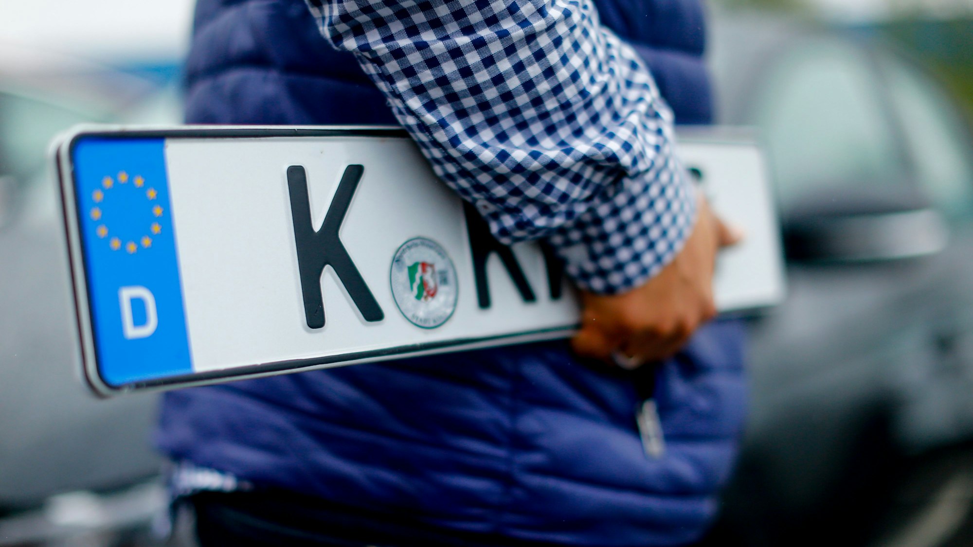 Ein Kunde trägt Nummernschilder vor der Kfz-Zulassungsstelle in Köln-Poll