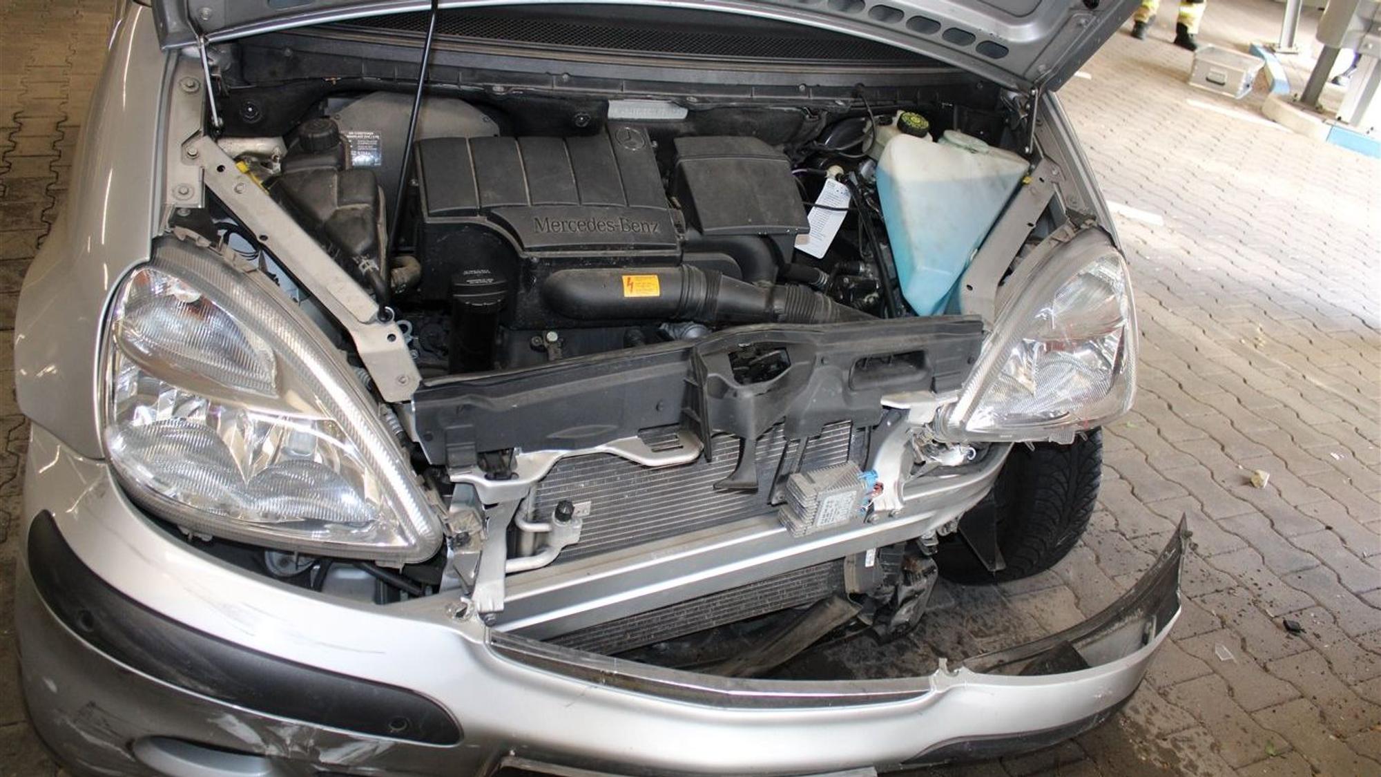 Ein zerbeultes Auto der Marke Daimler-Chrysler mit herunterhängender Stoßstange ist zu sehen.