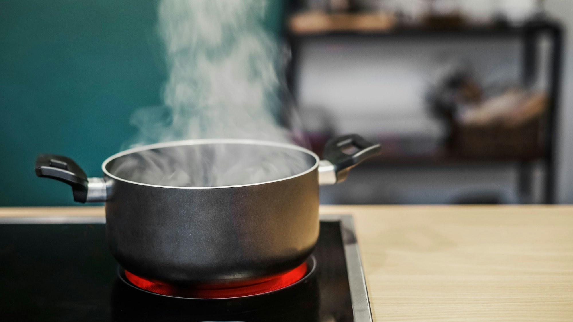 Ein Kochtopf steht auf einer Herdplatte, Wasserdampf steigt empor.