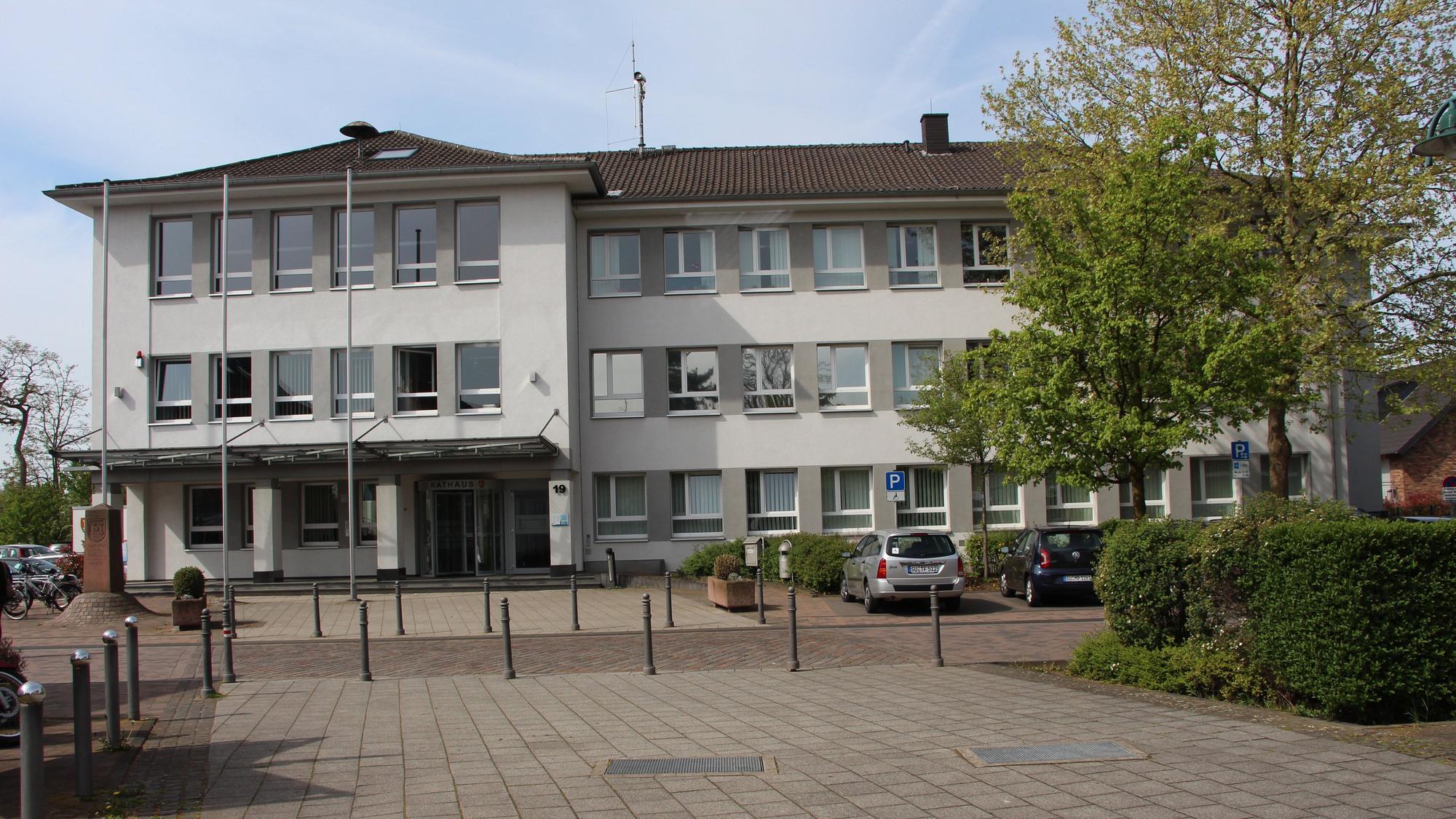 Ein heller, mehrstöckiger Bau mit Parkplätzen davor.