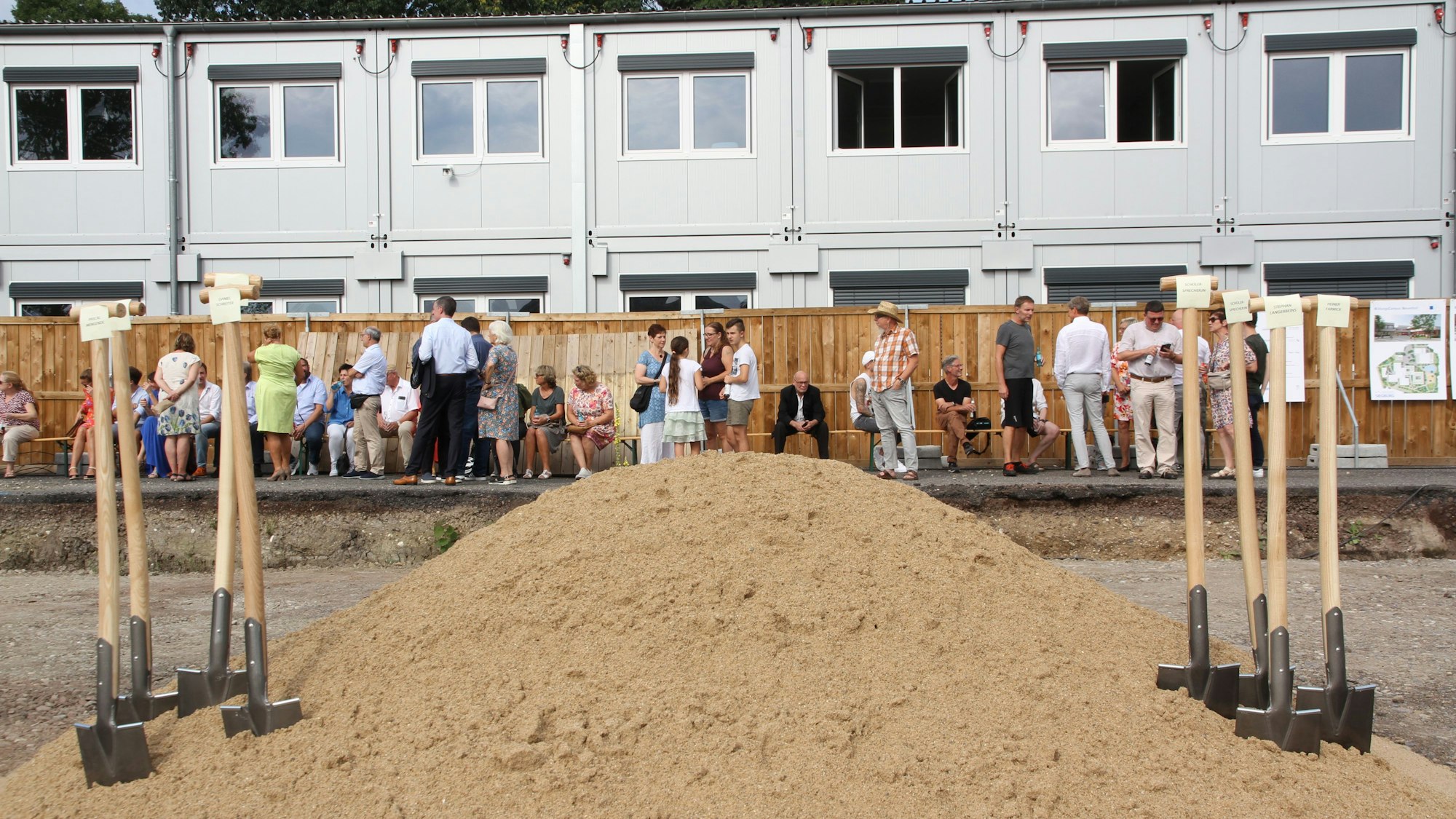 Spaten stecken in einem Sandhaufen für den symbolischen Baubeginn des Bildungscampus Neuenhof