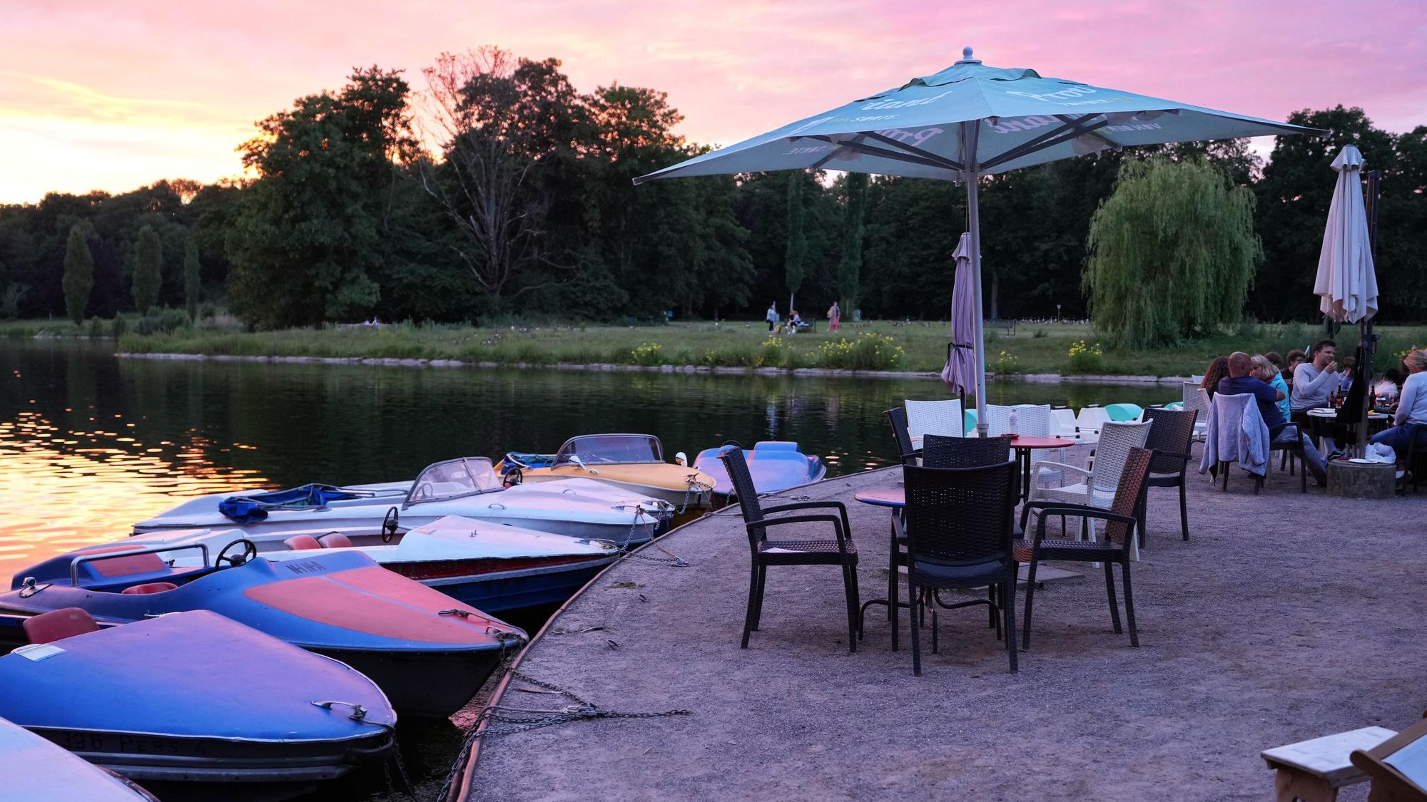 Das Ufer des Kalscheurer Weihers im Sonnenuntergang, Stühle mit Sonnenschirmen sind aufgestellt.