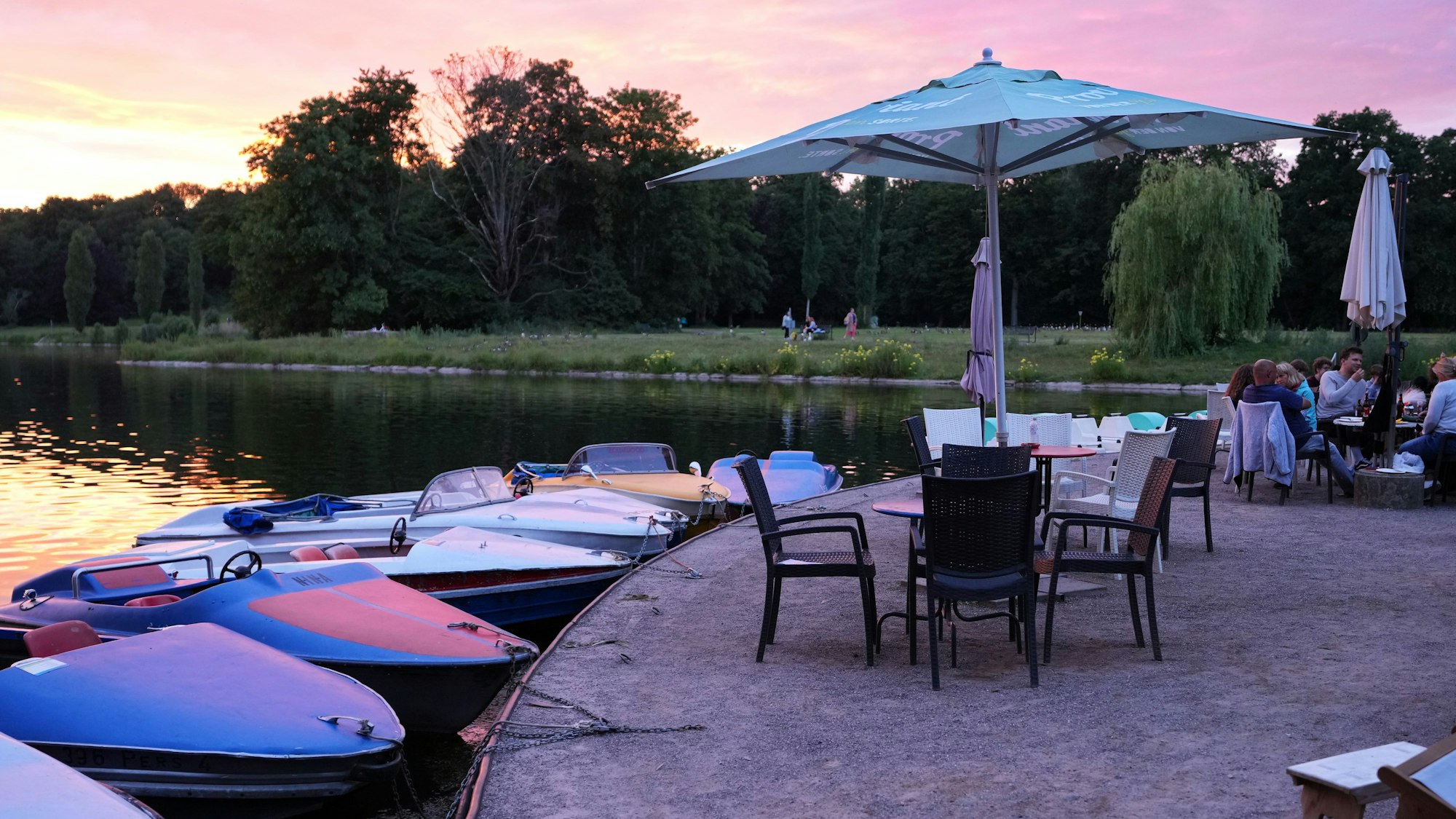 Das Ufer des Kalscheurer Weihers im Sonnenuntergang, Stühle mit Sonnenschirmen sind aufgestellt