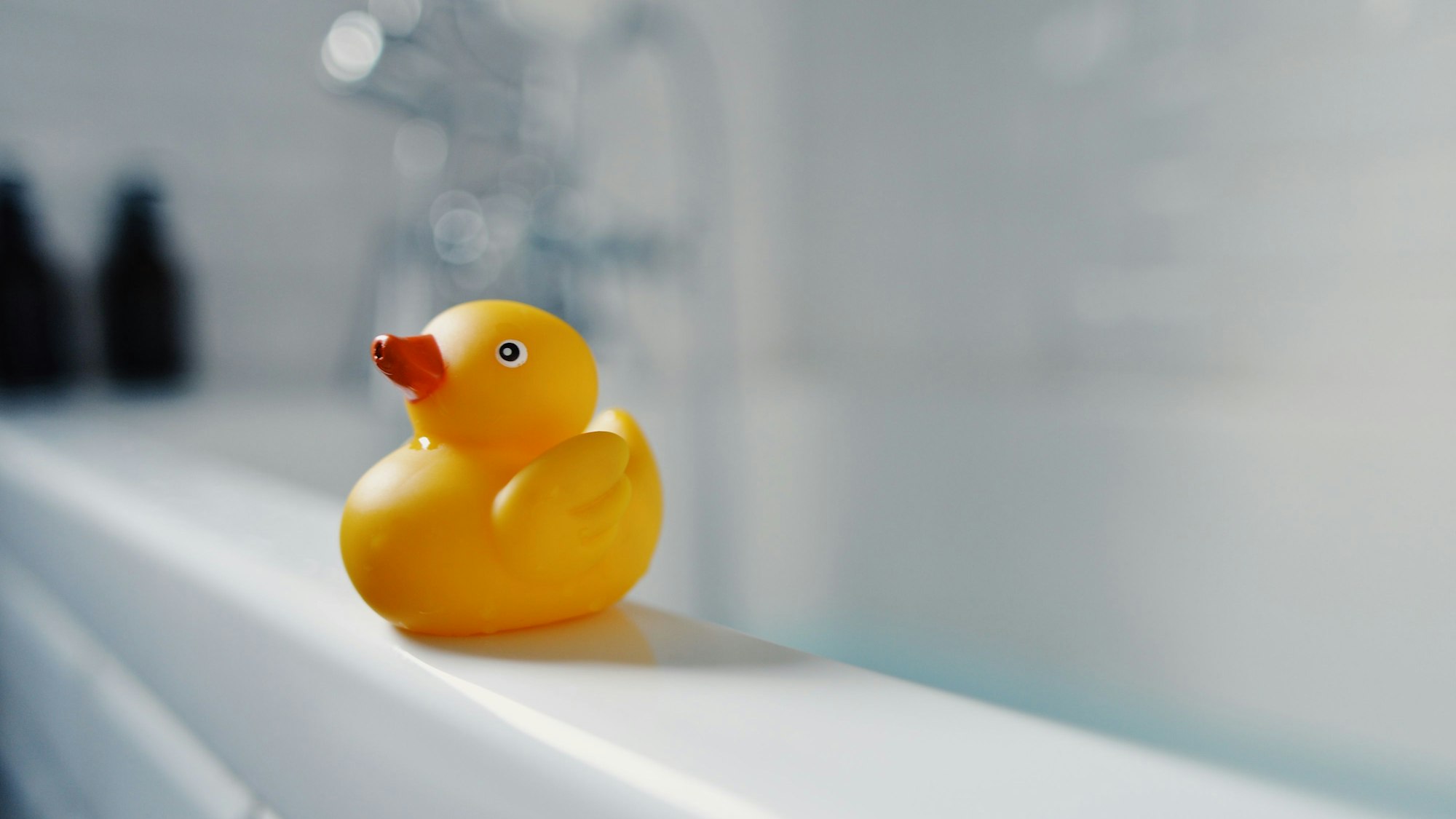 Eine Badeente steht auf dem Rand einer Badewanne