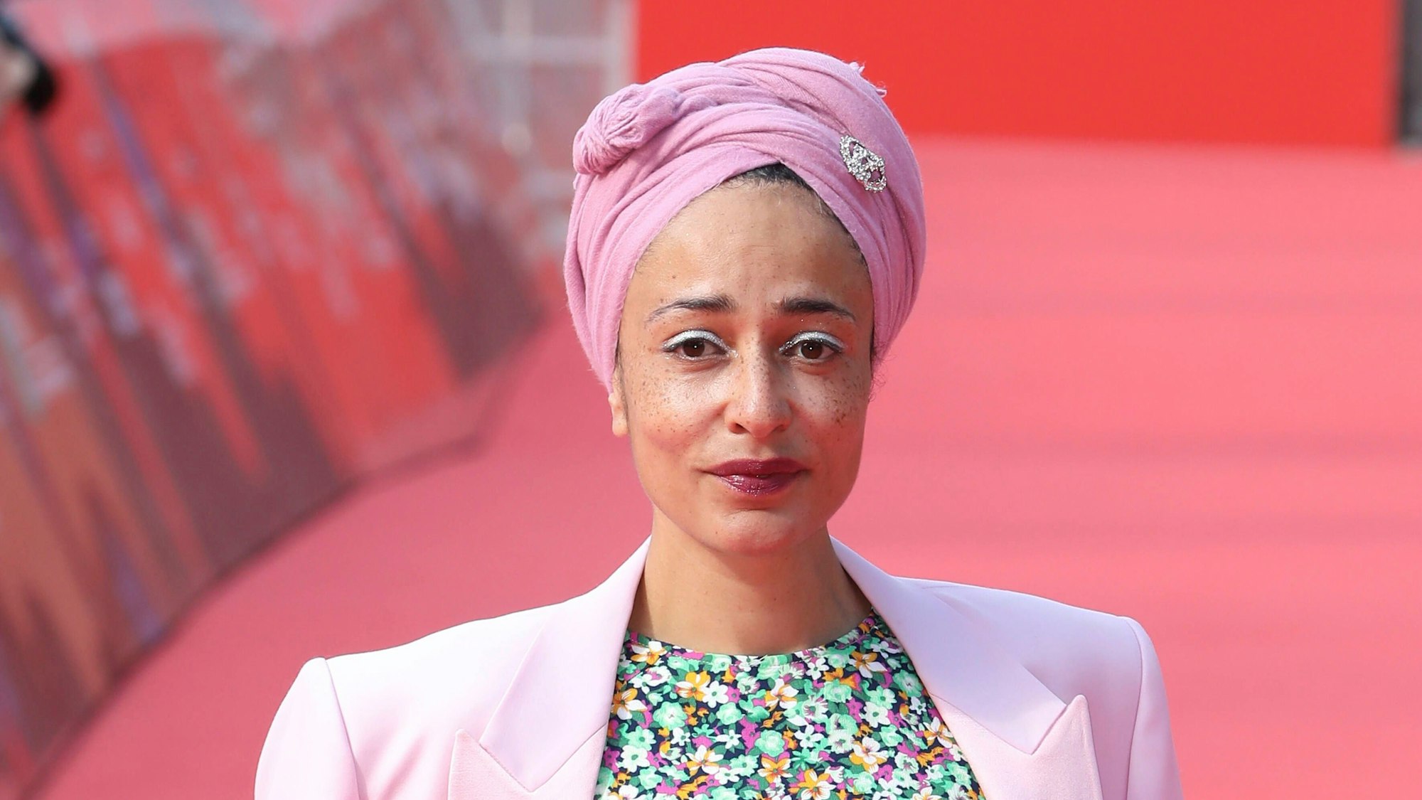 Zadie Smith trägt ein buntes Kleid und steht auf dem roten Teppich eines Filmfestivals.