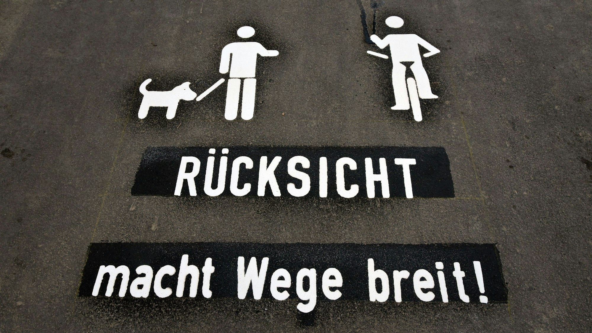 Eine auf den Boden gemalte Schrift mahnt Gassigänger und Radfahrer: Rücksicht macht Wege breit!
