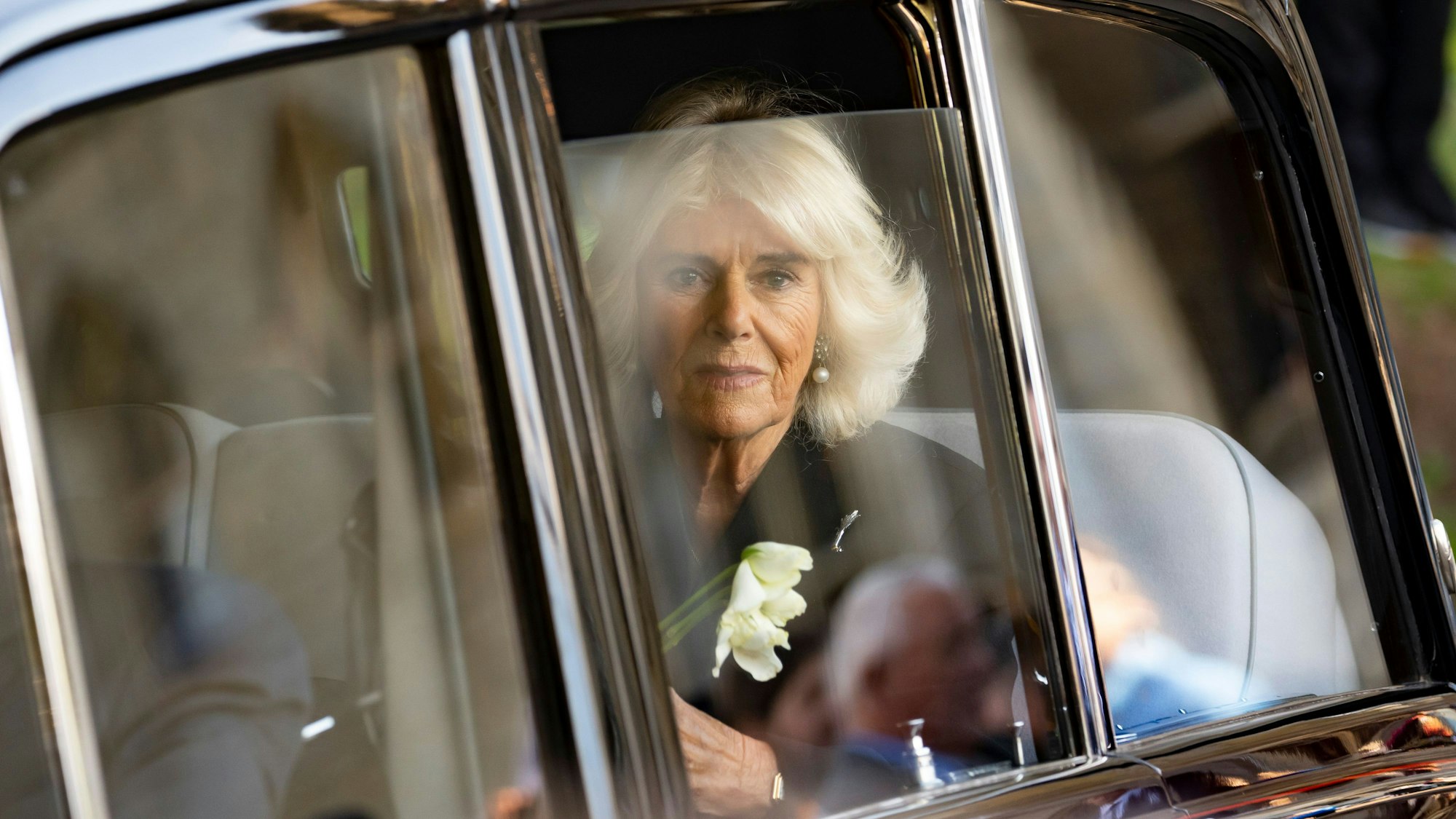 Camilla sitzt in einem Auto und schaut durch die Scheibe.