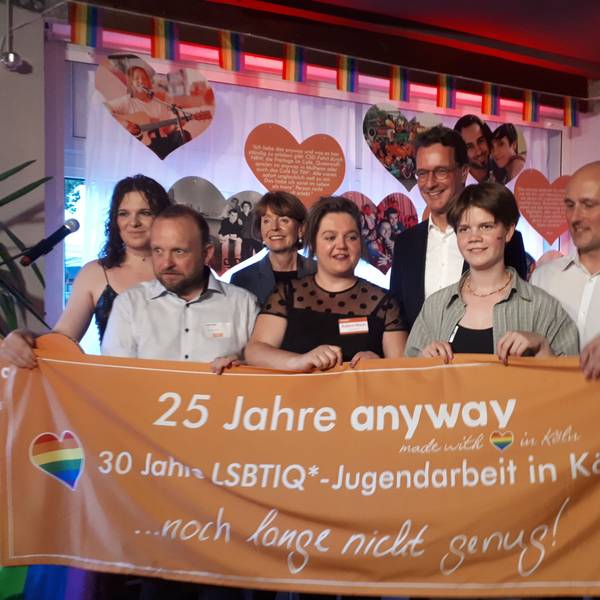 Die Feiernden halten gemeinsam ein Schild in die Höhe.