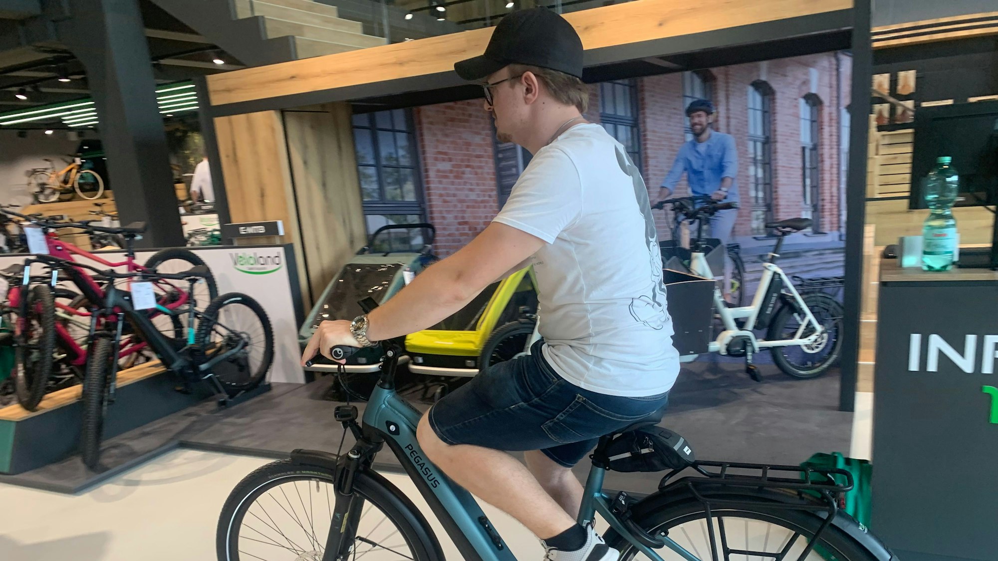 Auszubildender Dominik Lohr fährt ein E-Bike zu seinem Platz im Ladenlokal, wo es früh den Verkauf präsentiert wird.