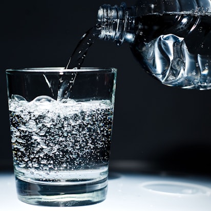 Sprudelwasser wird aus einer Flasche in ein Glas geschüttet.