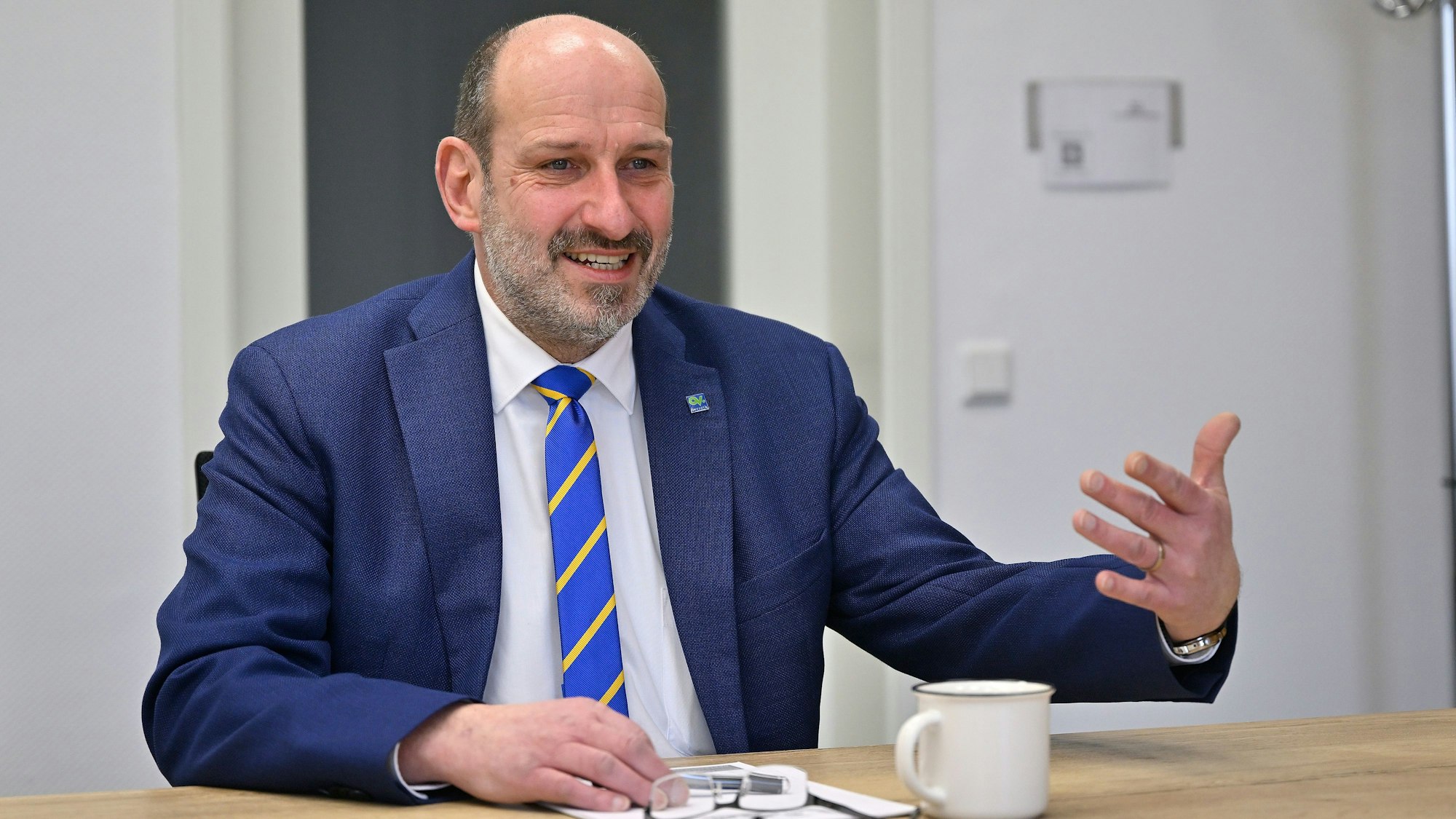 Overaths Bürgermeister Christoph Nicodemus sitzt an einem Tisch und spricht.