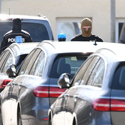 Einsatzkräfte der Polizei stehen nach einer Razzia an Einsatzfahrzeugen (Symbolbild).