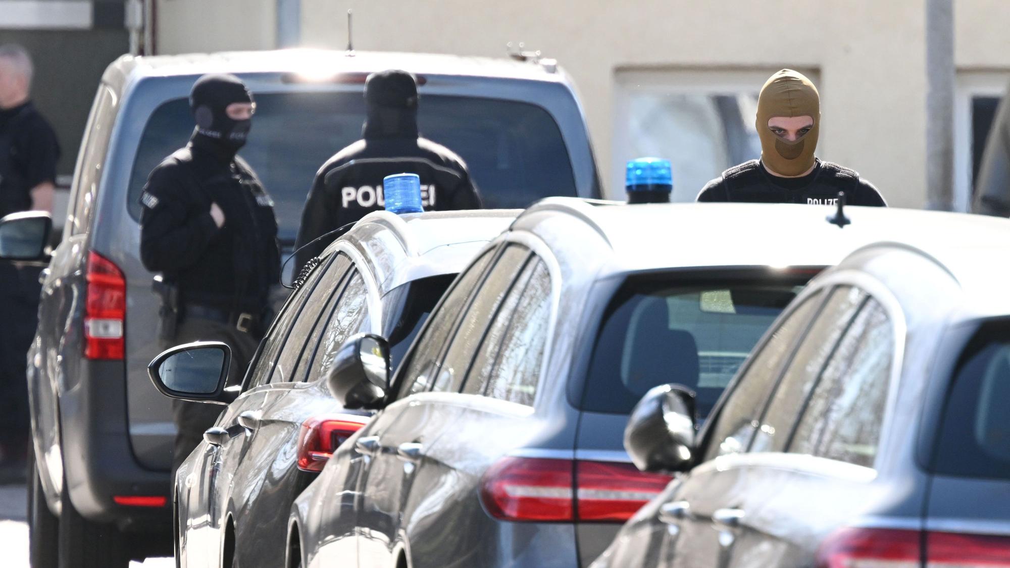 Einsatzkräfte der Polizei stehen nach einer Razzia an Einsatzfahrzeugen (Symbolbild).