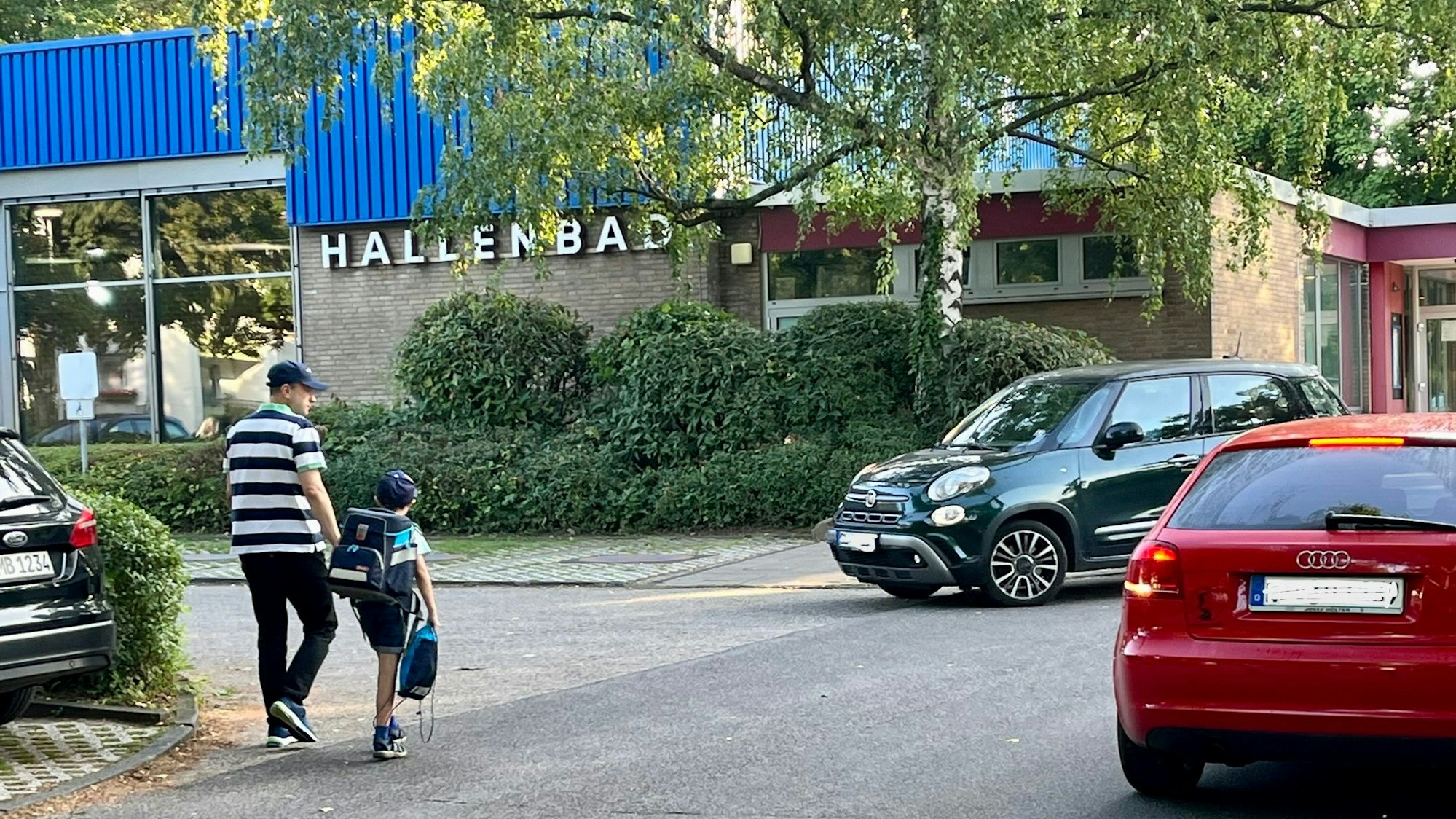 Kinder gehen am Hallenbad Bergisch Neukirchen entlang.