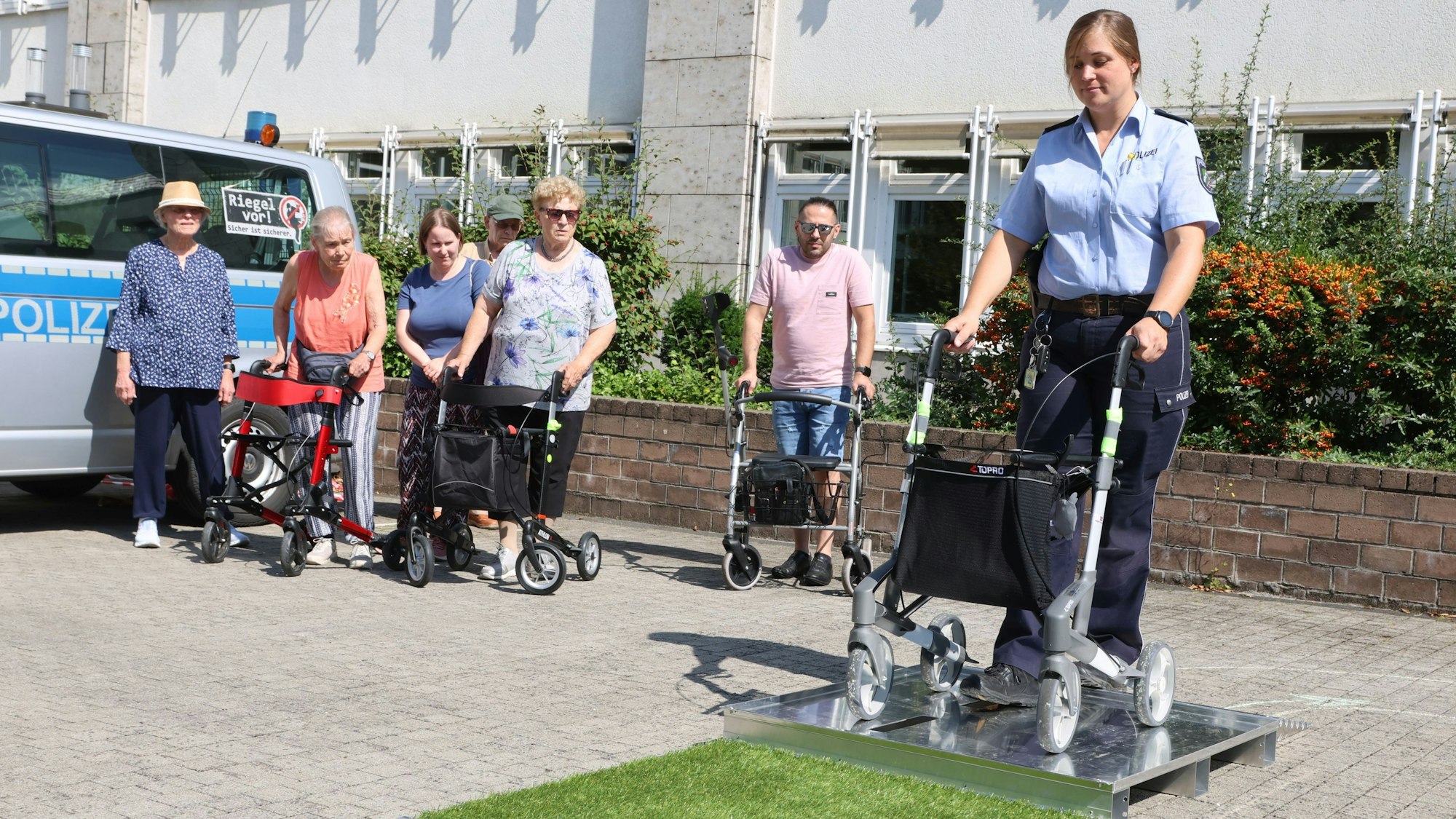 Auf dem Gummersbacher Rathausplatz steht eine Polizistin am Rollator vor einer Stufe.