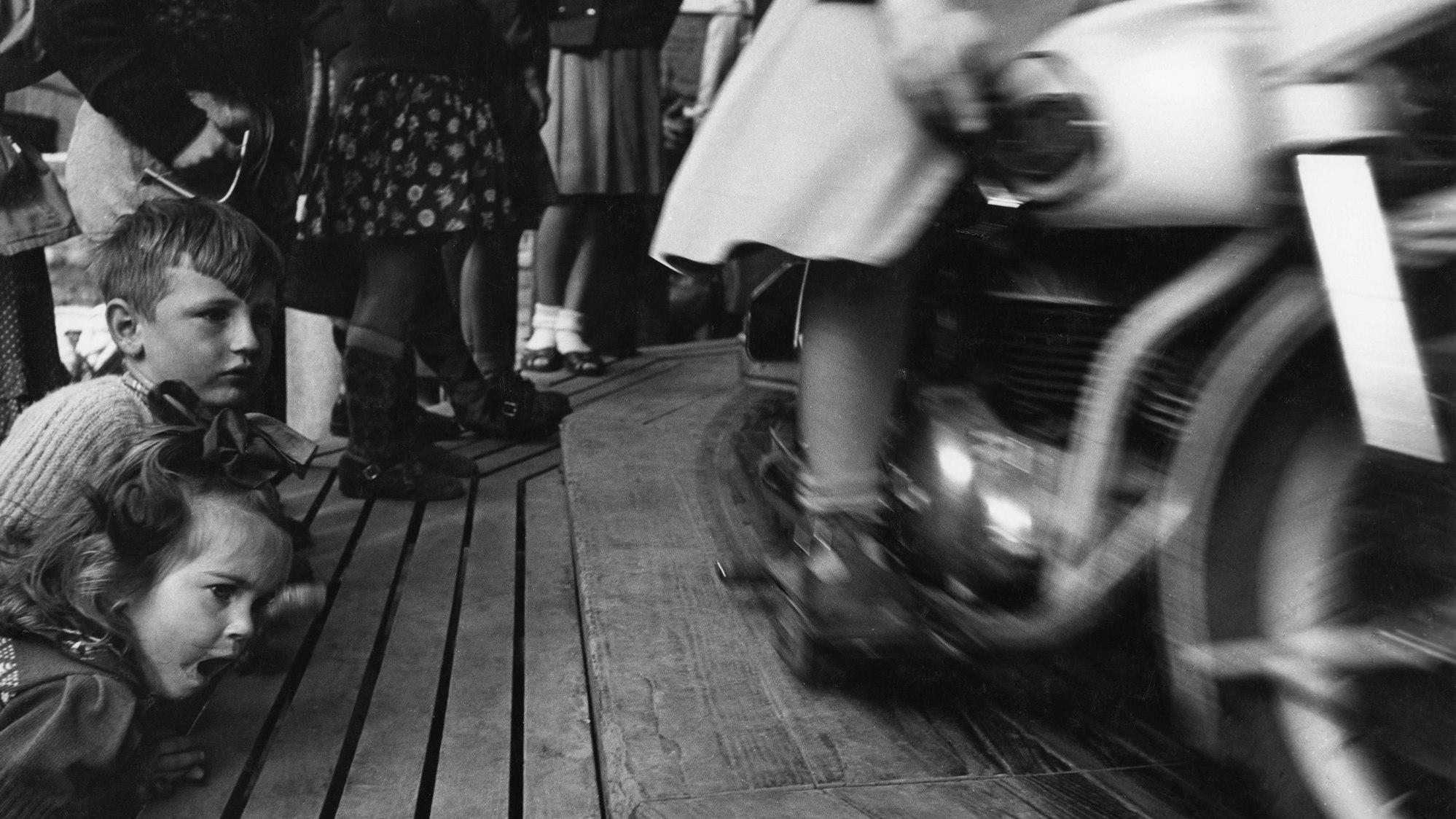 Kinder stehen staunend vor einem Karussell auf dem Rummelplatz