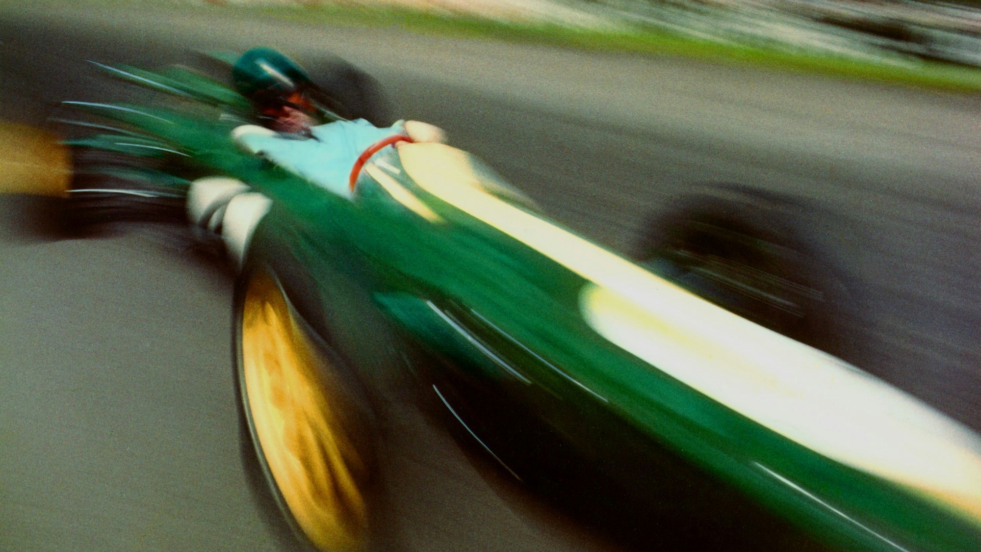 Fotografie eines grünen Rennautos, das durch die Geschwindigkeit verwischt und verzerrt wird.