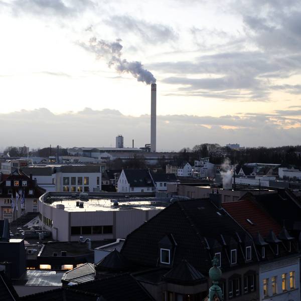 Die Innenstadt von Bergisch Gladbach, im Hintergrund ein qualmender Fabrikschornstein