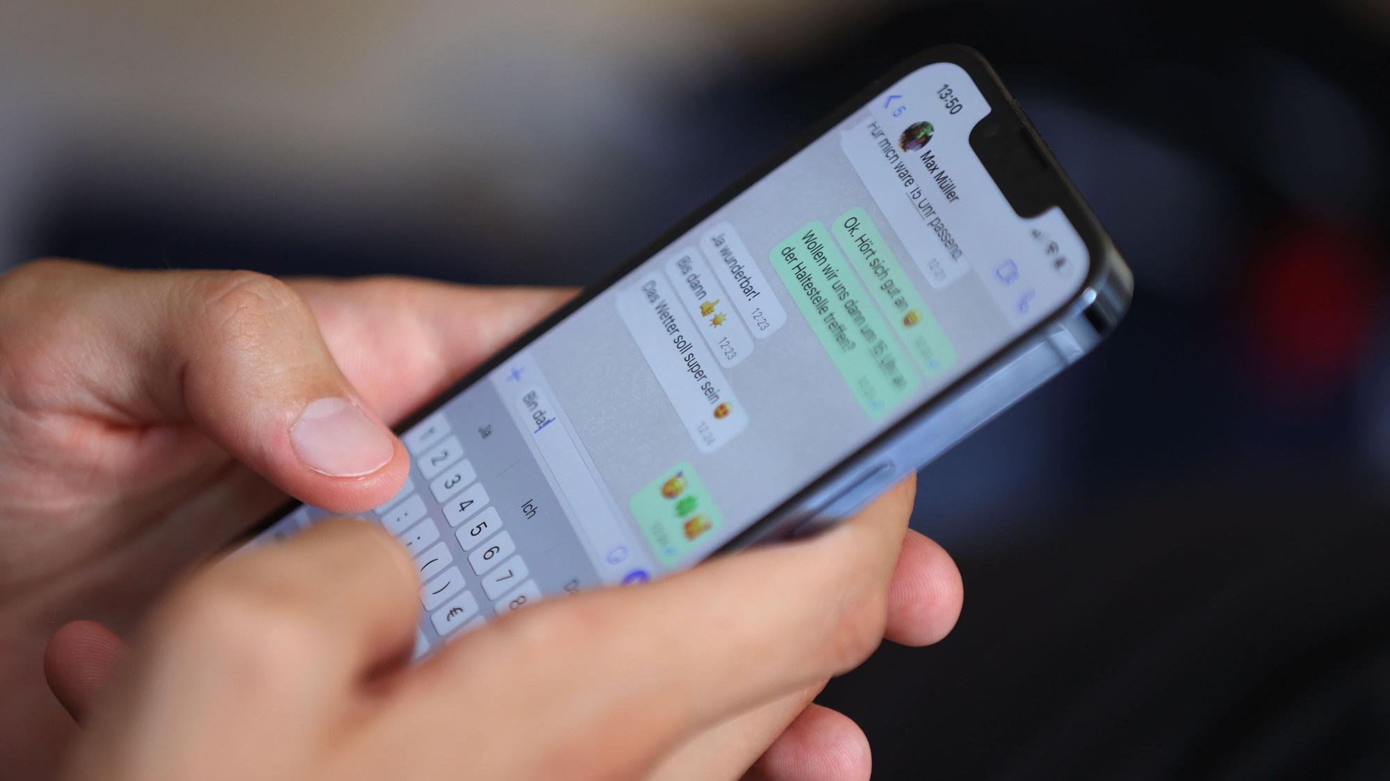 Ein junger Mann tippt auf einem Smartphone eine WhatsApp Nachricht.